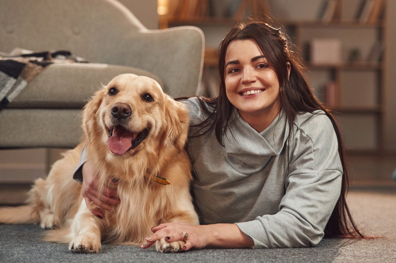 A smiling woman with her golden retriever dog